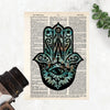 hamsa evil eye hand with blues and orange and black printed on a salvaged dictionary page