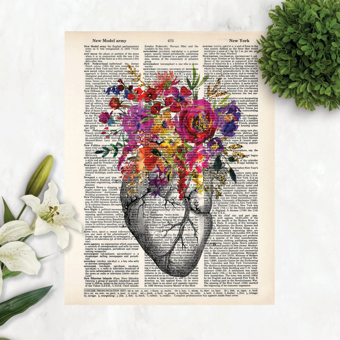 vintage etching of an anatomical heart topped with watercolor flowers in shades of pink, purple, yellow, and golden tones printed on a salvaged dictionary page