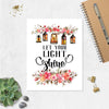 let your light shine is printed in black ink, at the top of the page there is a spray of pink and salmon colored flowers with five lanterns glowing amber with light, there are matching flowers and greenery at the bottom of the matte white paper