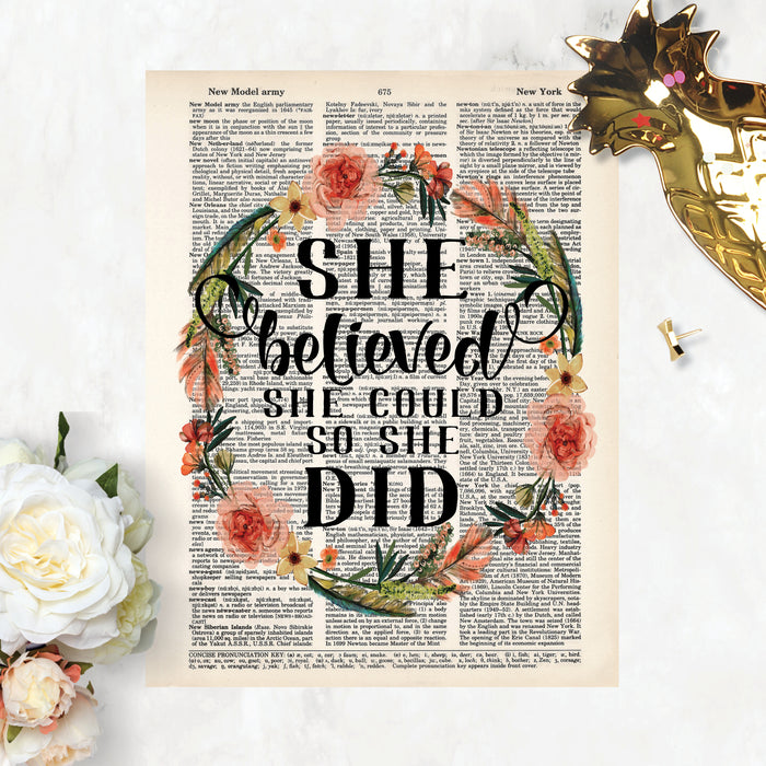 she believed she could so she did in black ink surrounded by a wreath in peach tone flowers and blue green feathers and greenery printed on a dictionary page