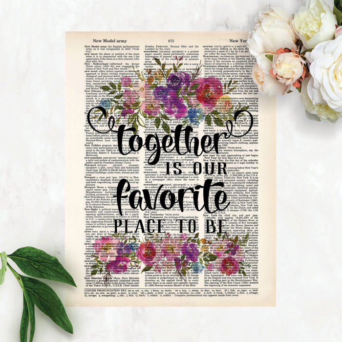 together is our favorite place to be with watercolor flowers in pinks, purples, blues with greenery top and bottom printed on a dictionary page