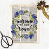 welcome to our home surrounded by a watercolor wreath in blue and yellow colors with greenery printed on a dictionary page